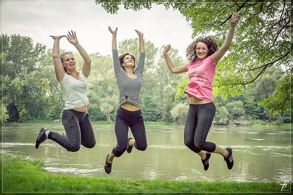 três mulheres alegres pulando em meio à natureza