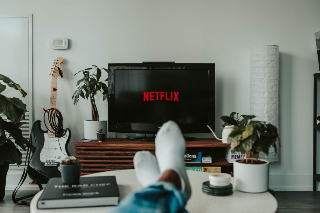 rapaz assistindo netflix e aprendendo inglês com os pés para cima